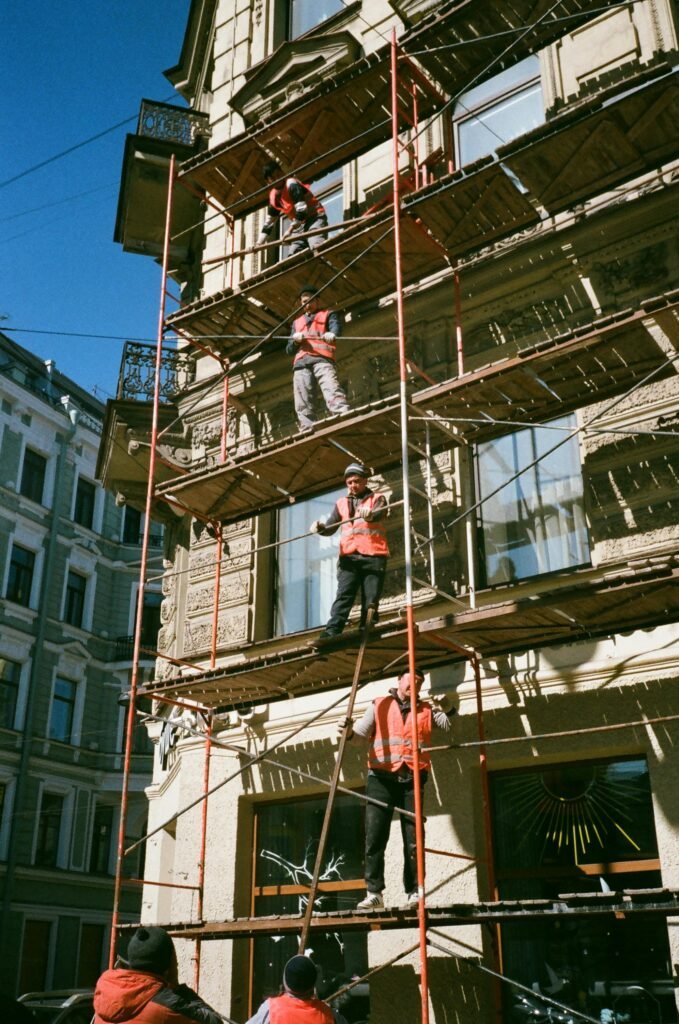 pexels photo 2209529 2209529 Construction workers on scaffolding renovating a building facade on a sunny day.